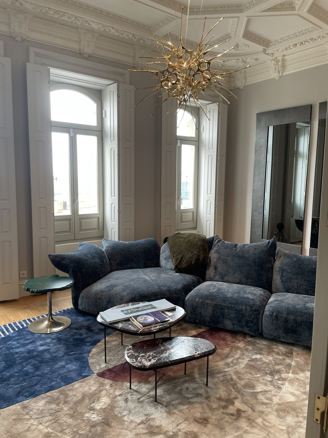 Living room in a period apartment with ornate plaster ceilings and a sculptural gilded Terzani chandelier